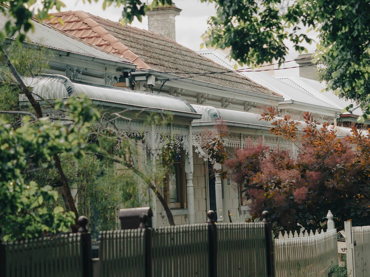 Victorian terrace houses with iron lace verandahs behind a picket fence